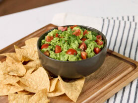 Bowl of chunky California avocado guacamole on a cutting board with tortilla chips