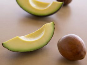 a slice of avocado next to a avocado pit