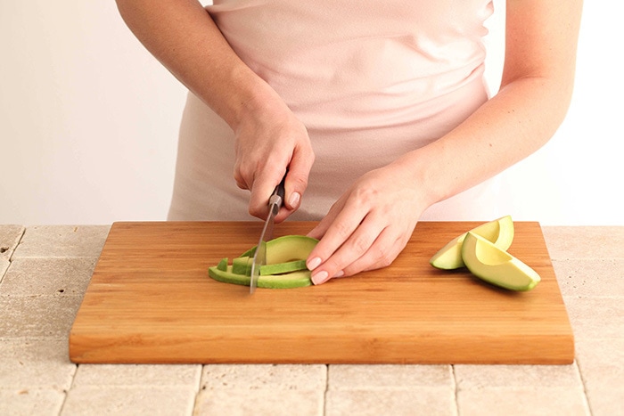 Fresh Market Avocado Cut In Half On A Wooden Cutting Board Next To A Knife  With More Avocados In The Background In A Cotton Reusable Shopping Bag  Stock Photo - Download Image