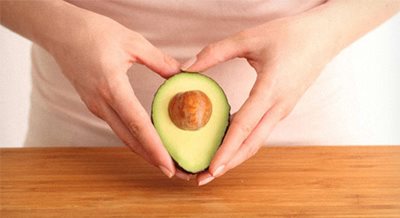 Two hands holding half of a California Avocado