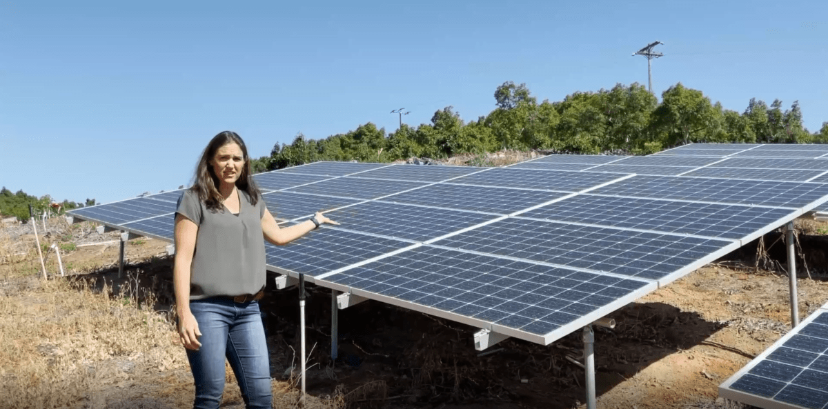 Grower Jessica Hunter in front of solar panels on a California Avocado grove.